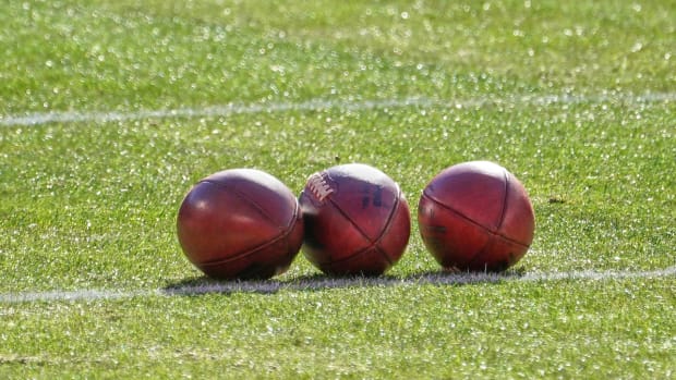Three footballs on a field.